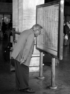 Reading a printed train schedule in an Italian station